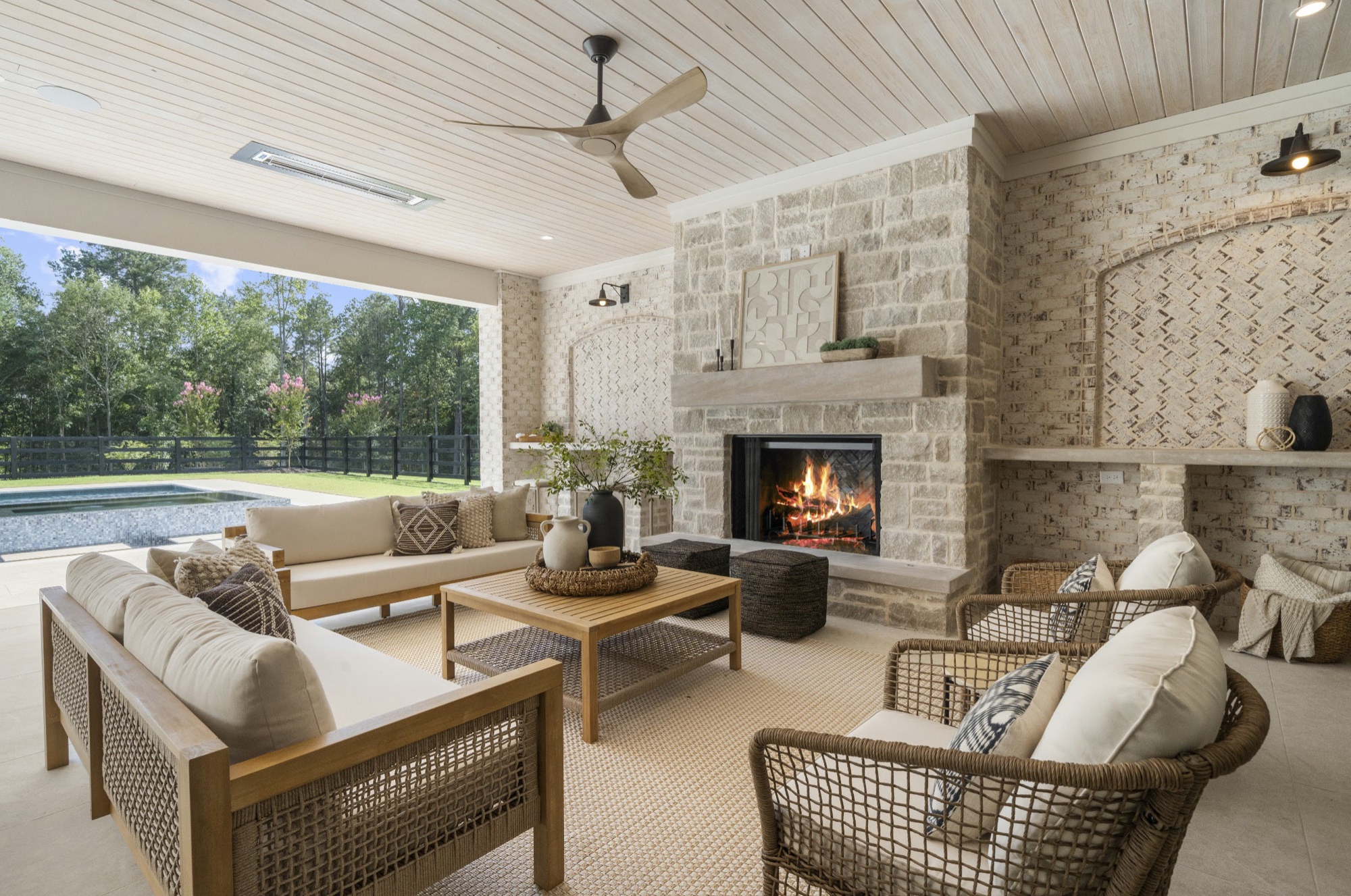 Covered outdoor room with stone fireplace, overlooking the pool