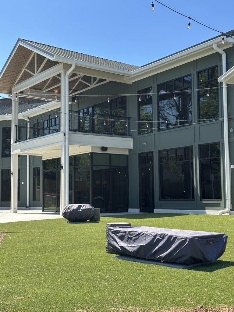 TapTown in Acworth before opening: a two-story building with a timber-truss portico and string lights over a turf beer garden.