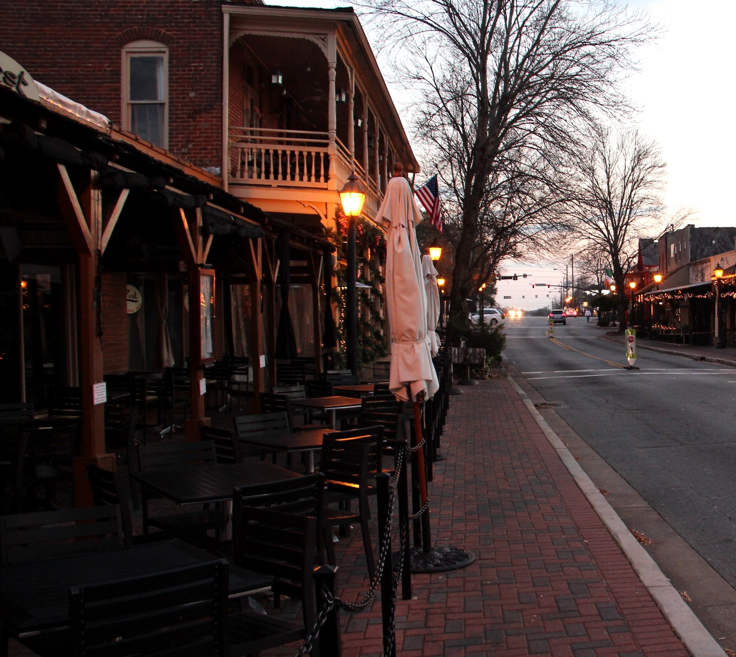 Canton Street in downtown Roswell at dusk, with historic storefronts, patio dining and brick sidewalks.